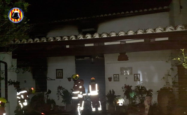 Los bomberos se afanan por extinguir el fuego en la vivienda de Barxeta donde se hundió parte del techo. 