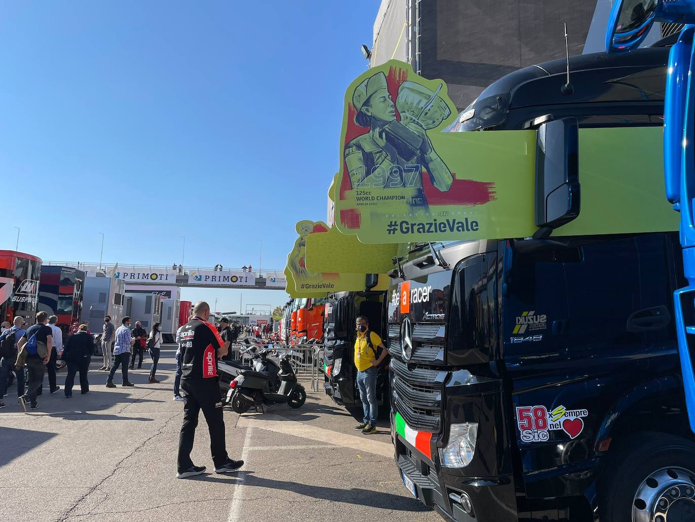 El paddock se ha teñido de amarillo este fin de semana. Como las gradas, que el sábado ya han expresado una muestra de intención de lo que será la carrera de este domingo. No es para nada exagerado afirmar que el 70% de los aficionados lucían merchandising de Valentino Rossi. Entre las muestras de homenaje que se le han dedicado por el momento, destaca la exposición de las nueve motos con las que ha sido campeón del mundo. Al lado está la 'Piazza Valentino Rossi', rotulada con una placa que simula ser de mármol y donde hay unos paneles amarilos que expresan los principales hitos del mito transalpino a lo largo de su carera. Más allá de esto, la mayoría de los camiones de los equipos tienen un panel, del mismo diseño, como muestra de gratitud al piloto por haber potenciado el Mundial de MotoGP durante sus más de 25 años de carrera. El propio piloto, en su mono, luce en la parte posterior este fin de semana un escueto pero representativo: 'Grazie'.