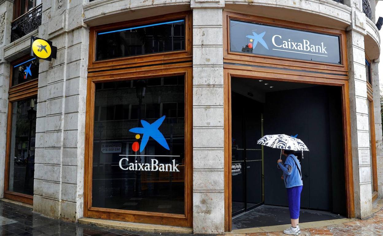 Una mujer que observa el interior de la sede de Caixabank.