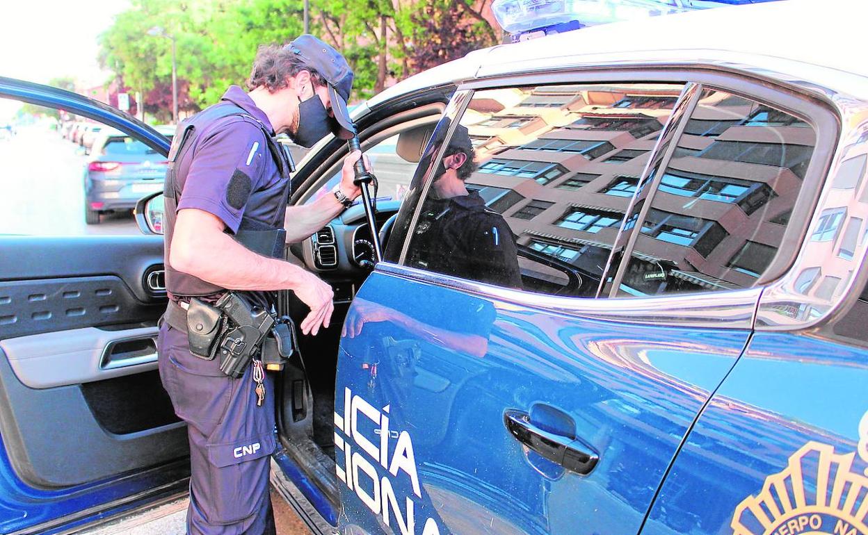 Un policía nacional se dispone a subir a un coche patrulla.