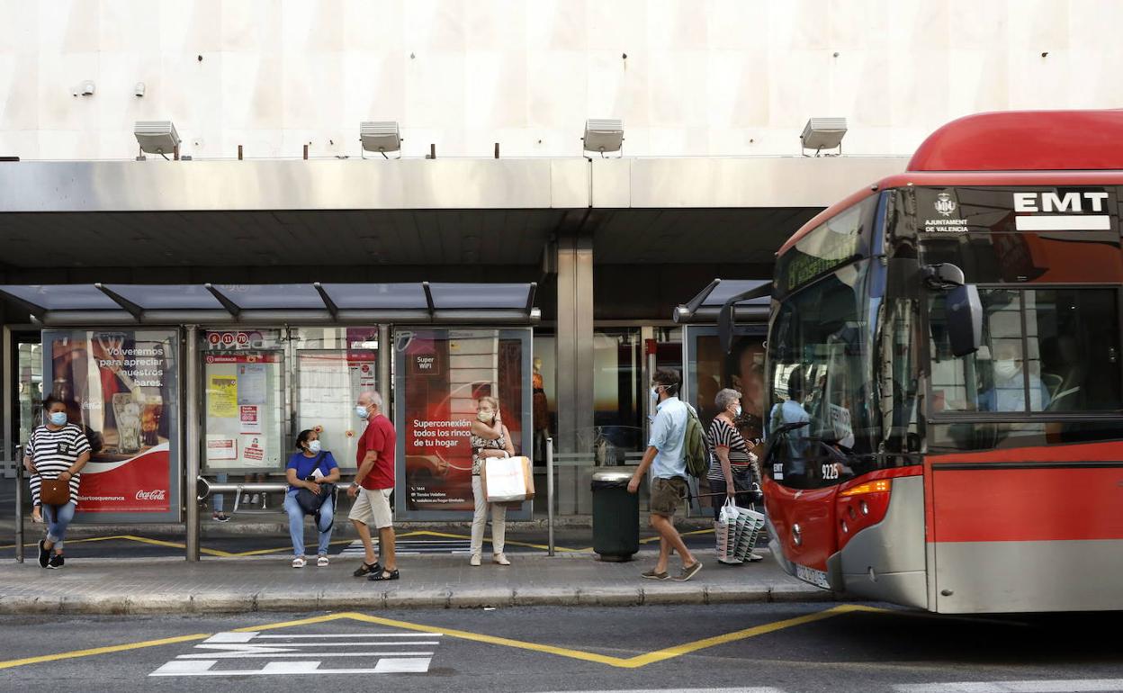 Varias personas esperan al autobús en una parada de la EMT.