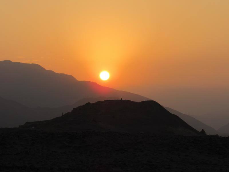 Fotografía cedida por Zona Arqueológica Caral que muestra la puesta de sol durante el solsticio de junio sobre la fachada lateral de la pirámide mayor de Caral