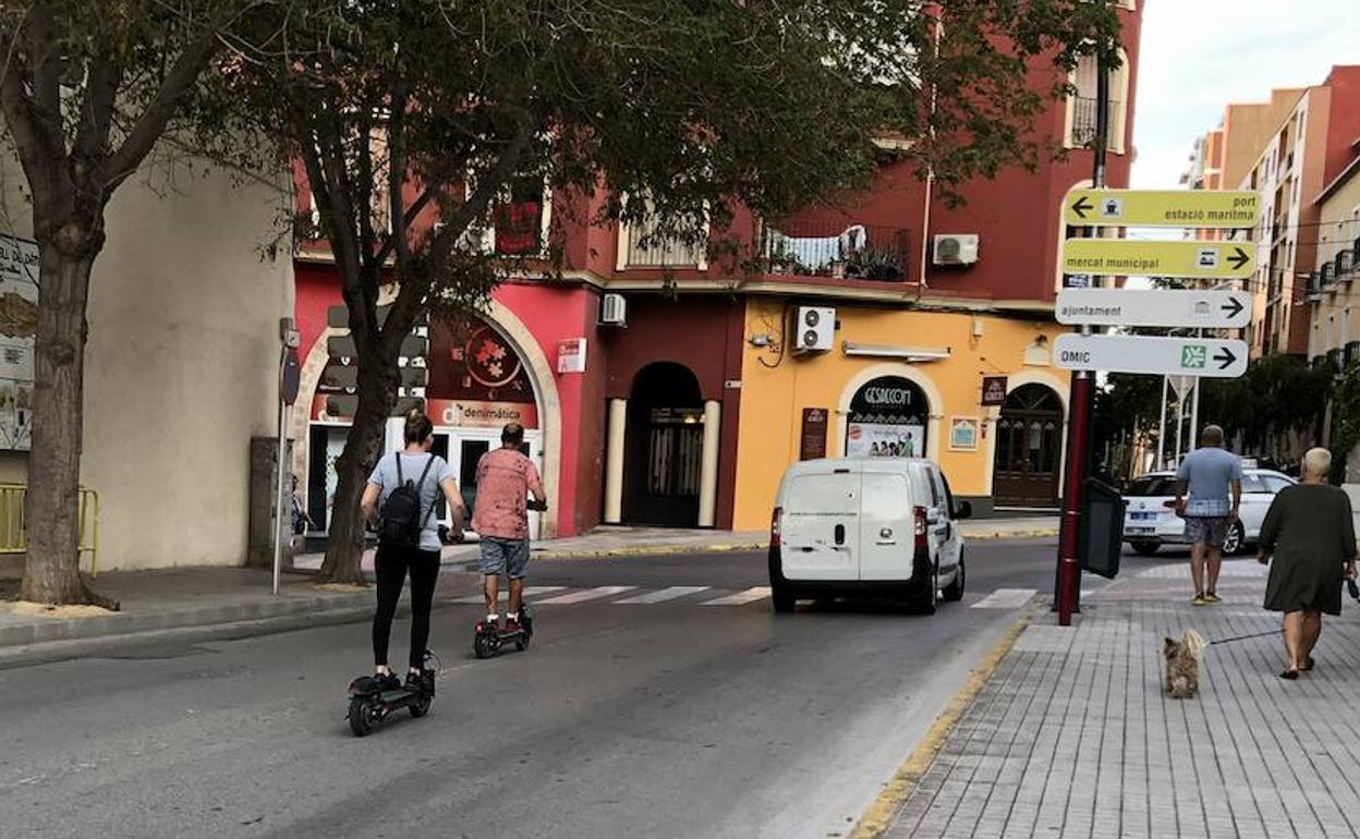 Dos patinetes circulando por la calle Foramur de Dénia. 