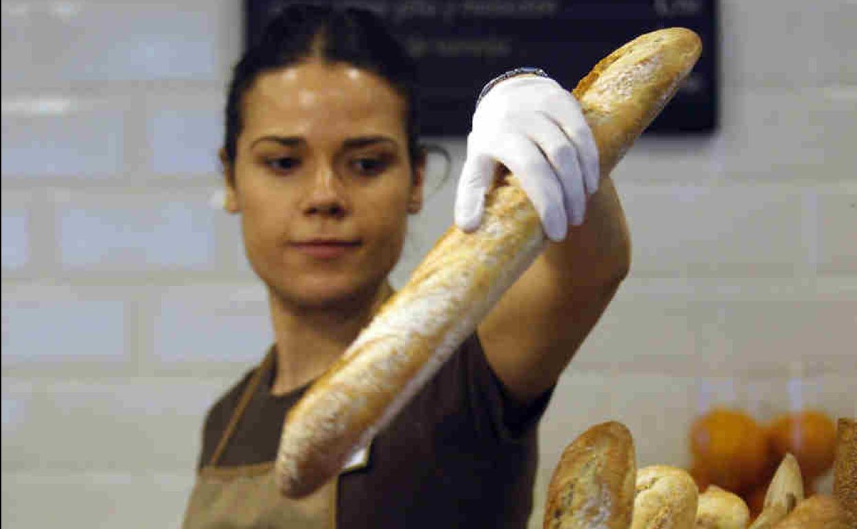 Dependienta vendiendo una barra de pan.