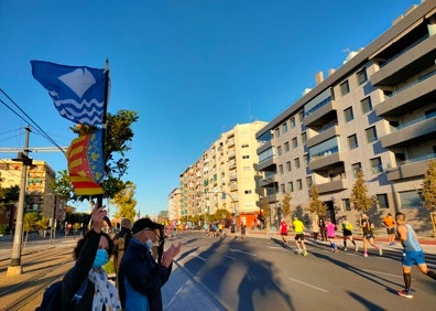 Imagen secundaria 1 - Arriba, los corredores a su paso por la calle Eugenia Viñes. Abajo a la izquierda, Pilar con la bandera valenciana y la de la Isla de Wight. Abajo a la derecha, los corredores pasando por la Avenida de los Naranjos. 