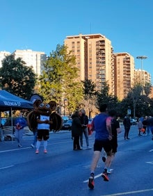 Imagen secundaria 2 - Arriba, la carrera frente al estadio de Mestalla. Abajo a la izquierda, los corredores pasan frente a una bandera del Valencia CF. Abajo a la derecha, el rat penat, símbolo del equipo, anima a los deportistas. 