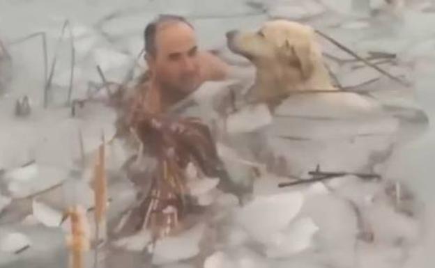 Uno de los agentes alcanza al perro entre el hielo.