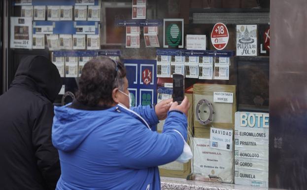 Un hombre escoge su décimo de la Lotería de Navidad. 