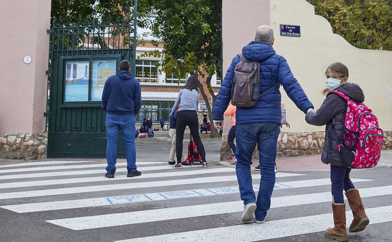 Un hombre camina con su hija de 8 años hacia la entrada del colegio La Salle de Paterna, esta mañana. 