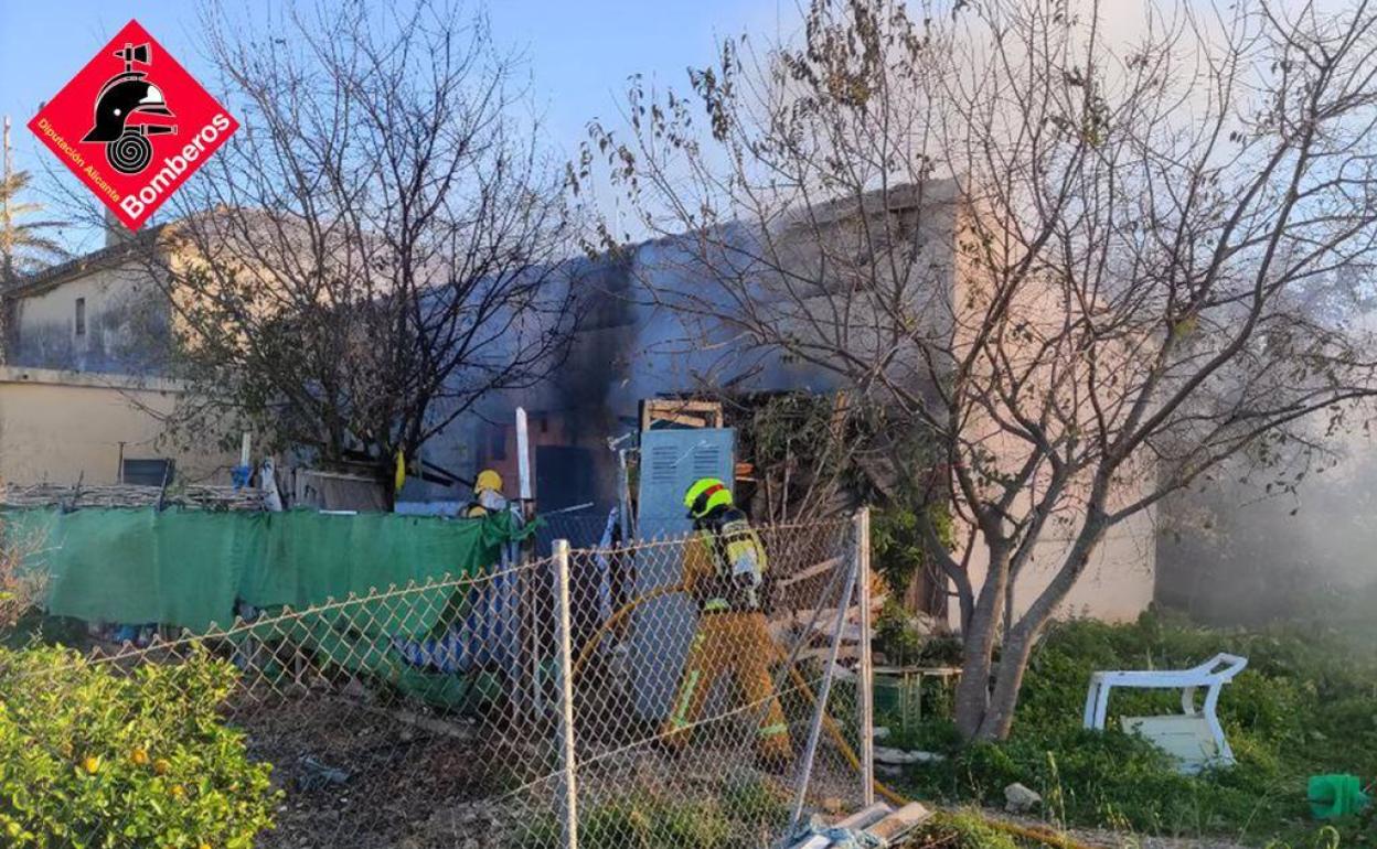 Los bomberos sofocando el fuego desde el exterior de la casa. 