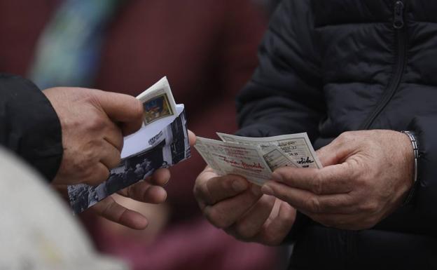 Dos hombres intercambian décimos de Lotería. 