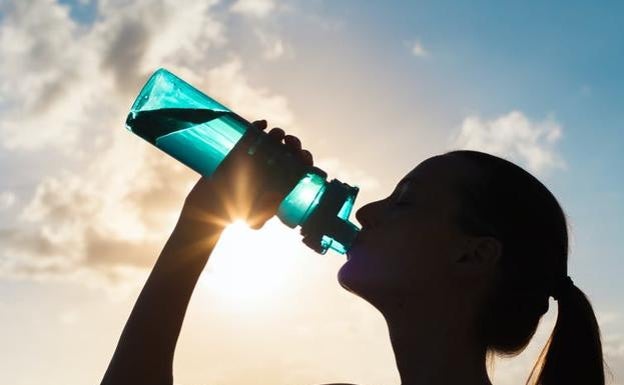 Mujer bebe agua de una cantimplora. 