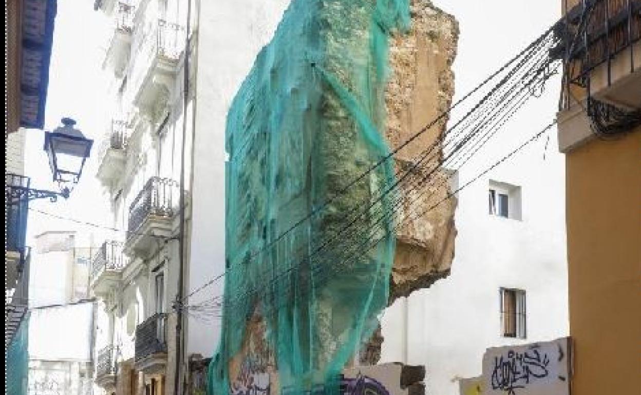 Un vecino pasa junto a la muralla de la calle Salinas.