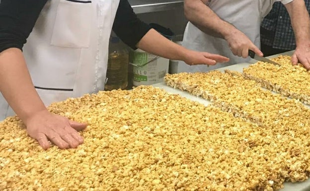 Momento en el que la pasta de turrón se extiende sobre una mesa para proceder a cortarlo en pastillas. 