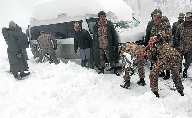 Miembros del Ejército paquistaní tratan de liberar uno de los vehículos atrapados por la nieve.