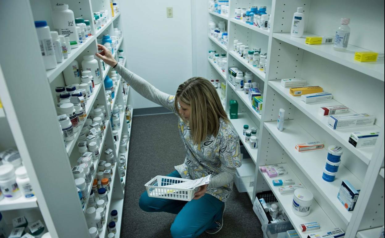 Farmacéutica buscando medicamentos en las baldas de la farmacia.