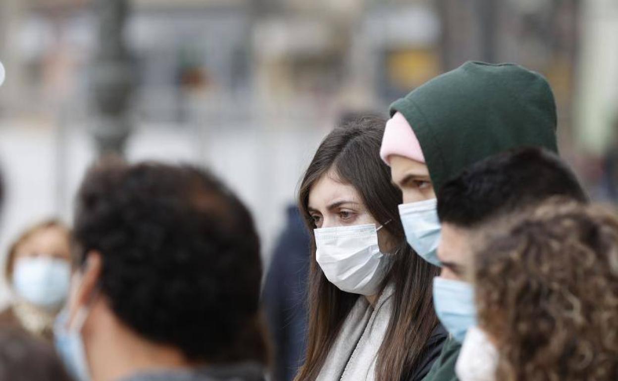 Gente pasea con mascarilla por Valencia.