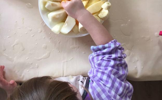 Un niño coge una pieza de fruta en la escuela infantil El Pati de El Puig.