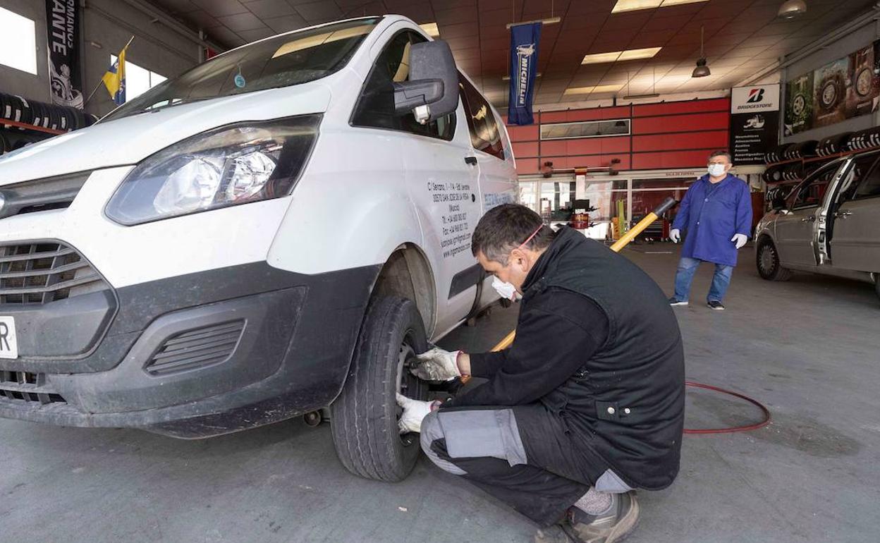 Un mecánico revisa una furgoneta en un taller. 