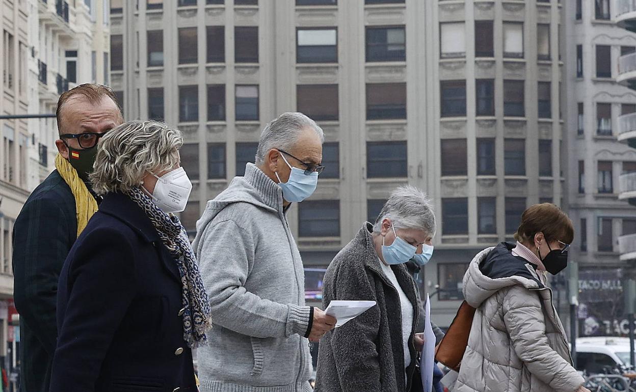 Varias personas pasean por Valencia con mascarilla. 