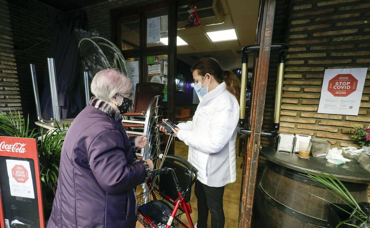 Una clienta espera que una empleada de hostelería verifique su pasaporte Covid. 