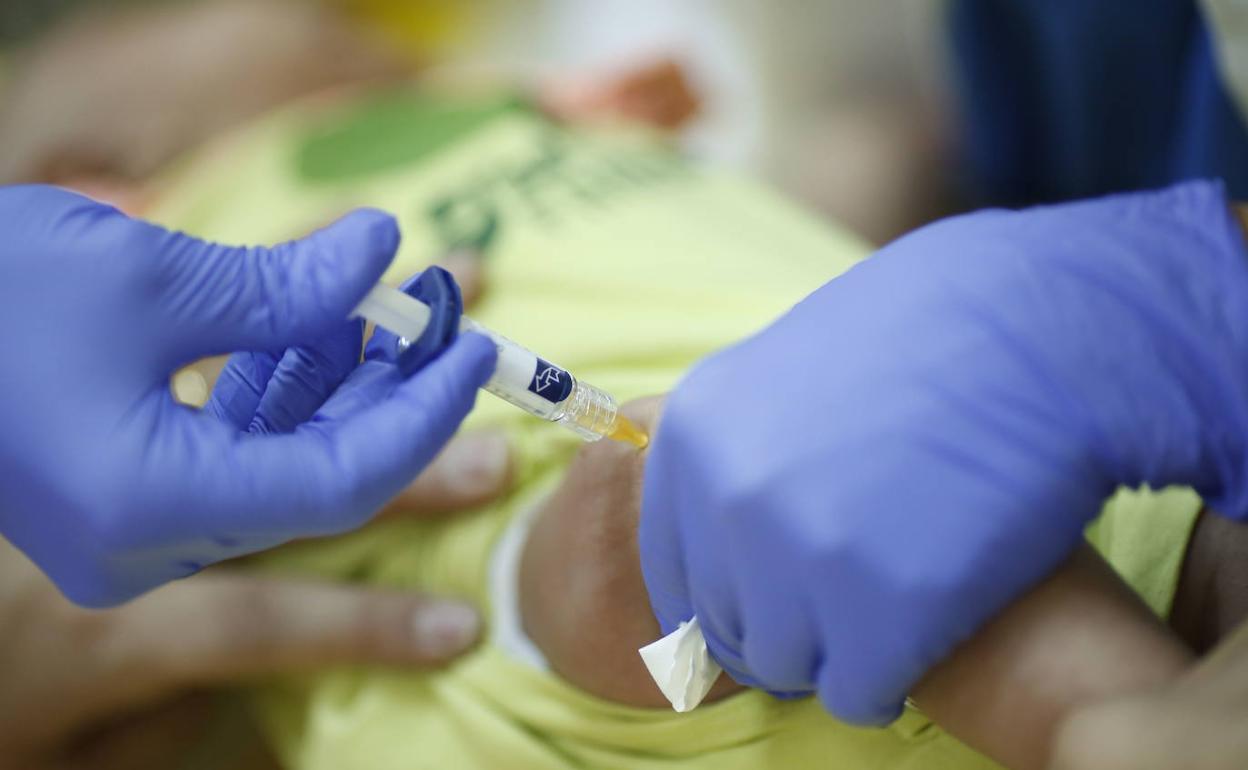 Personal sanitario administra una vacuna a un bebé.