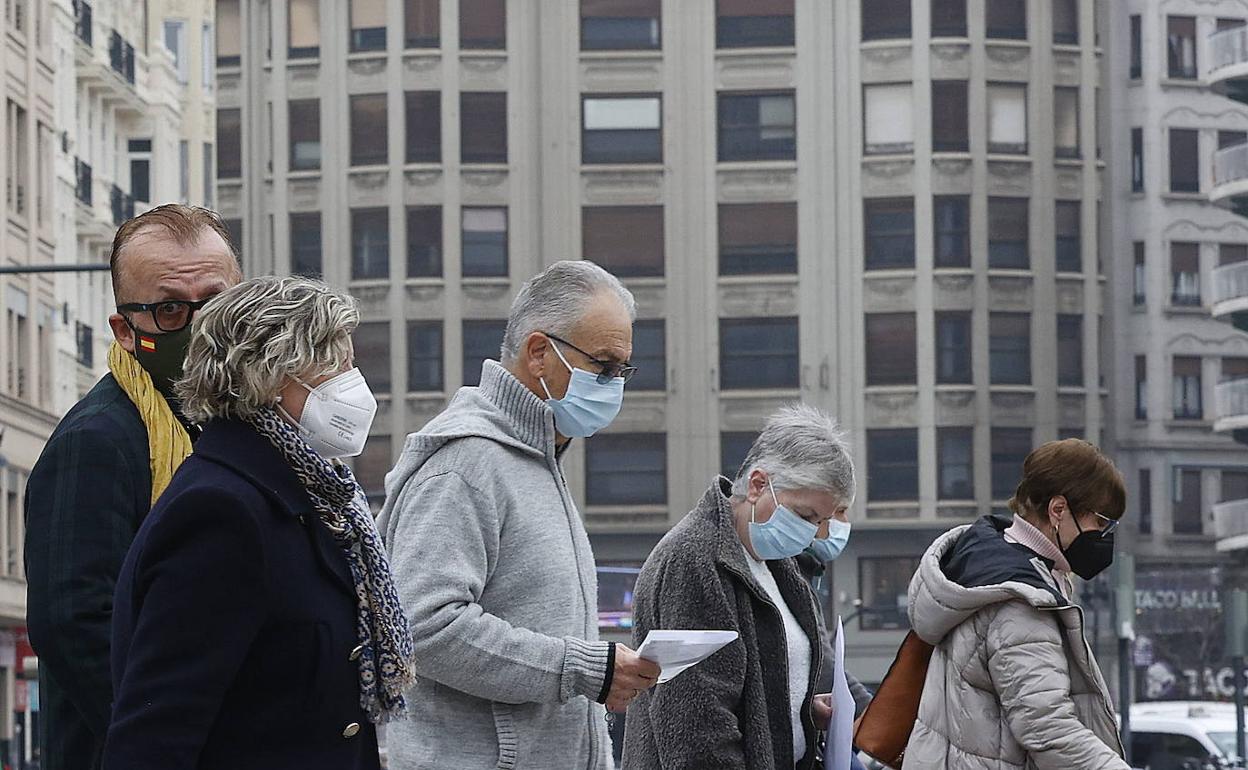 Varias personas pasean por Valencia con mascarilla. 