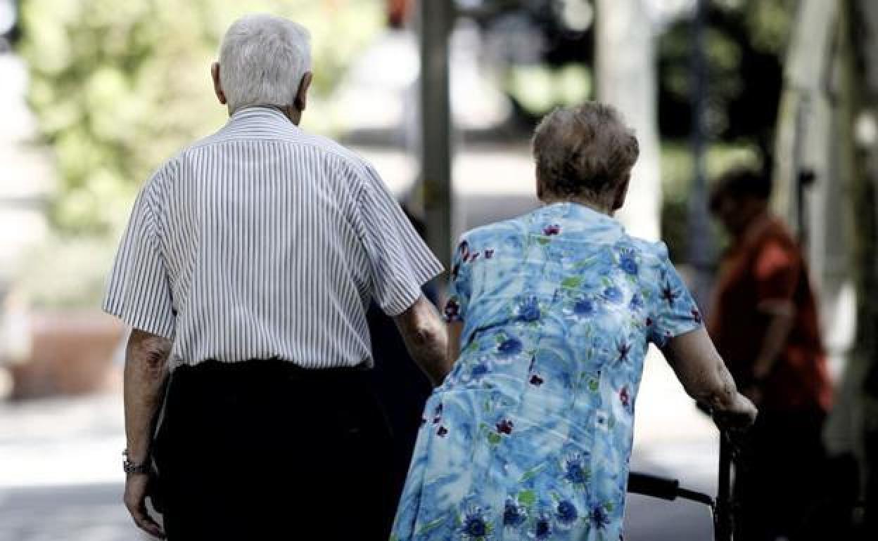 Una pareja de ancianos pasean por la calle. 