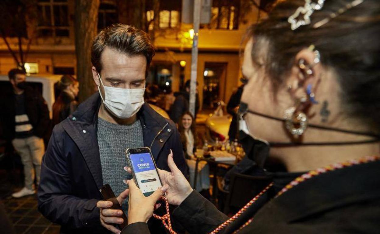 Joven muestra el pasaporte Covid para entrar a un bar en Valencia. 