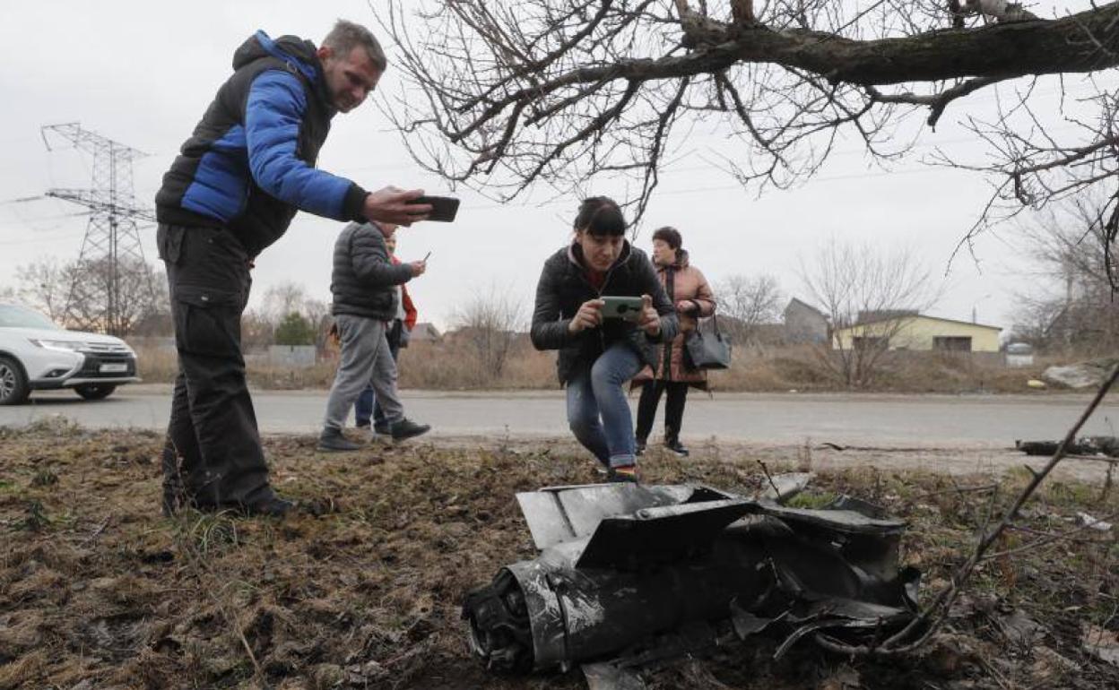 Unos ciudadanos toman fotografías de los restos de un cohete lanzado contra Ucrania. 