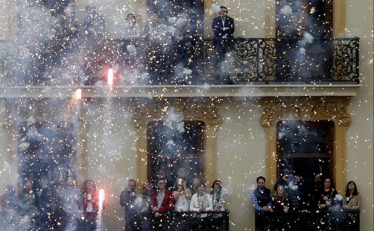 Decenas de personas disfrutan de una mascletà desde los balcones de los edificios recayentes a la plaza del Ayuntamiento. 