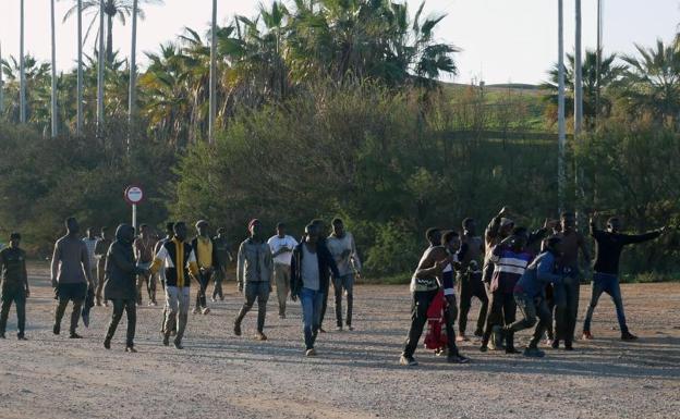 Imagen principal - Arriba, algunos de los inmigrantes que han saltado la valla este jueves. Abajo, imagen de la valla y un agente con herramientas empleadas para escalar. 