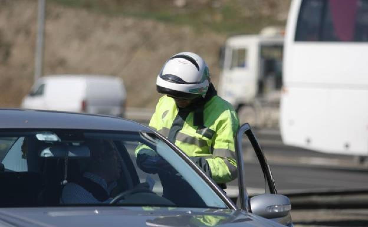 Un agente de Tráfico multa a un conductor en una carretera. 