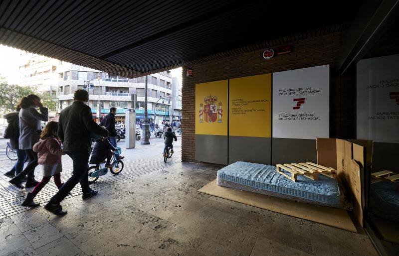 Una personas sin hogar coloca un colchón en el exterior del edificio de delegación del Gobierno en la calle Colón en Valencia. 