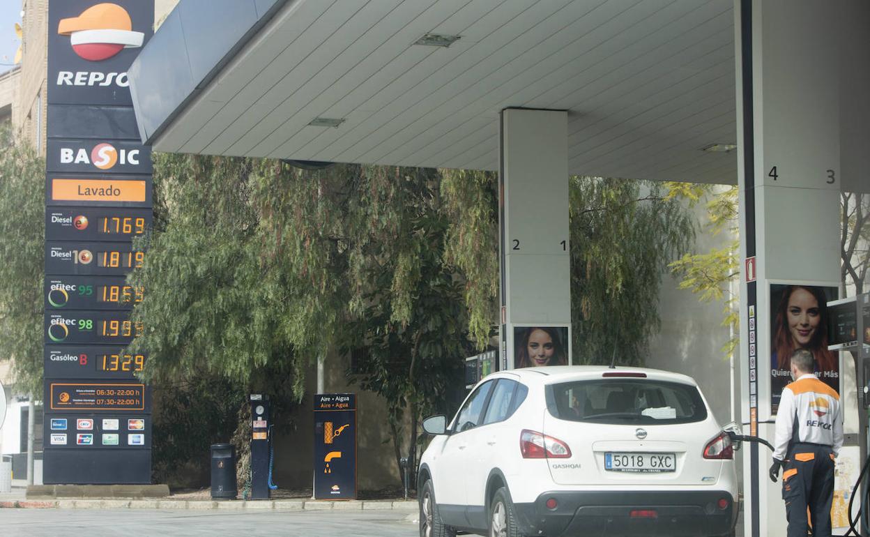 Un coche reposta en una estación ante el panel con el precio del combustible. 