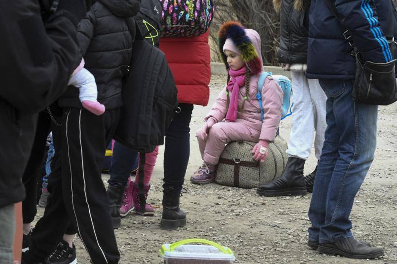 Una niña que trata de huir por la frontera de Moldavia descansa en una maleta.