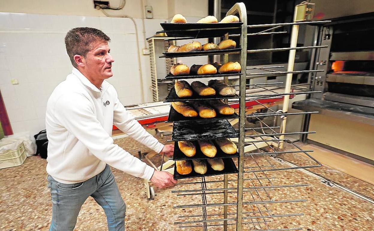 Nacho Olmos transporta bandejas de pan en su horno.