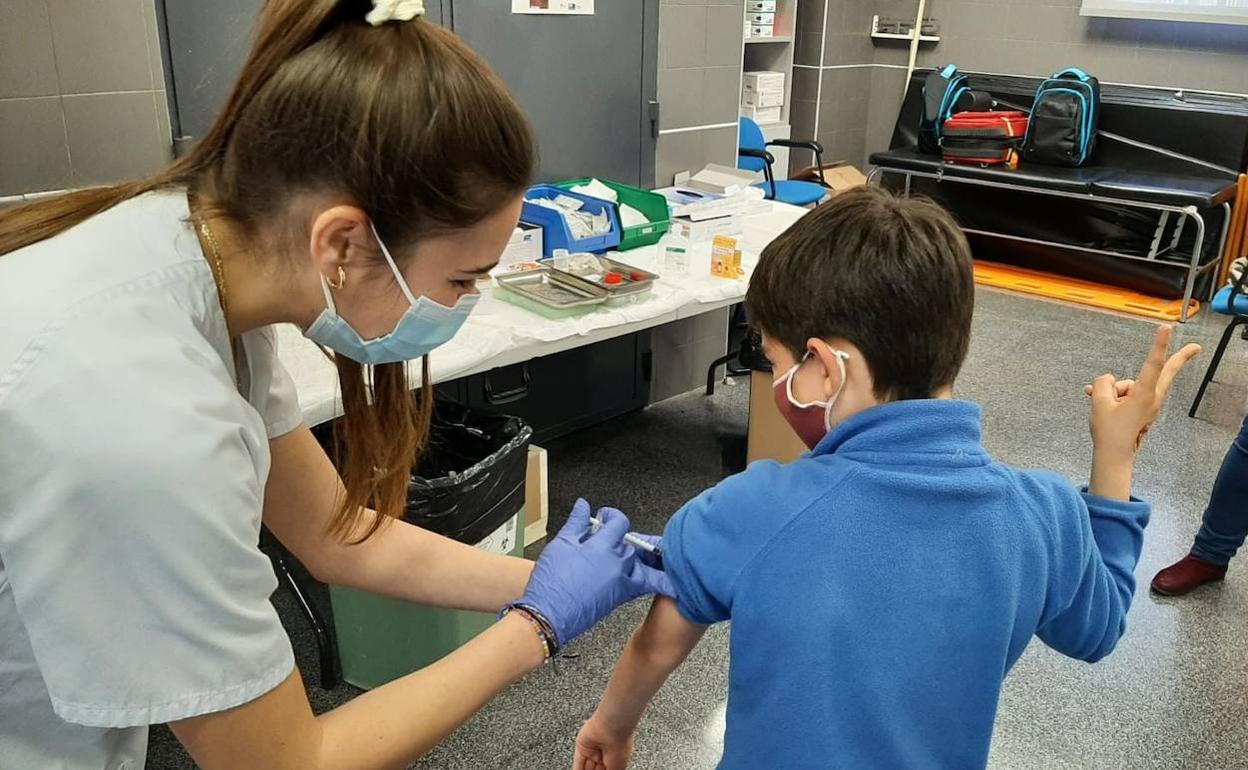 Personal sanitario administra la vacuna contra el Covid a un niño en un colegio de Xàtiva.