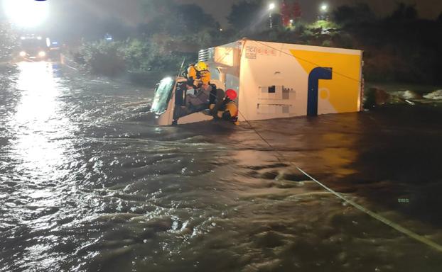 Los bomberos rescatan a los dos ocupantes de un camión momentos antes de ser arrastrado por el agua en Quart de Poblet