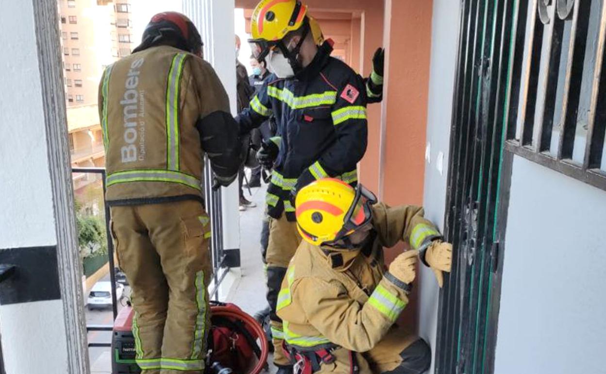 Los bomberos trabajan en la apetrura de la puerta de la vivienda, este sábado, en Benidorm. 