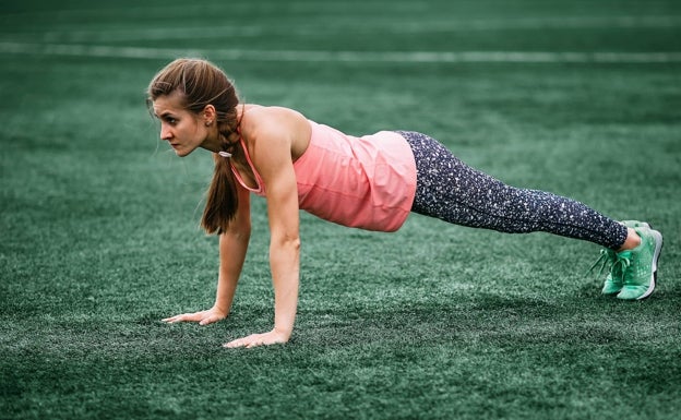 Una mujer deportista realiza un burpee. 