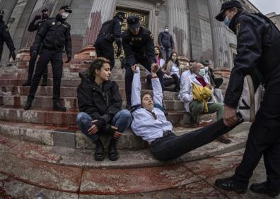 Imagen secundaria 1 - La fachada del Congreso tras la protesta; la Policía desalojando a los manifestantes; y una mujer pinta una de las columnas. 