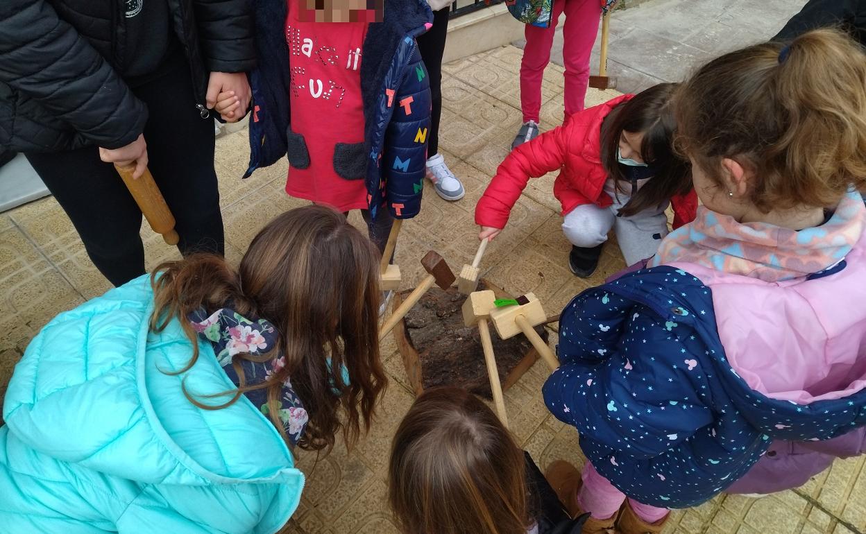 Los niños golpean un tronco para avisar de la llegada de la comitiva religiosa en  'la Salpassa' de Otos.