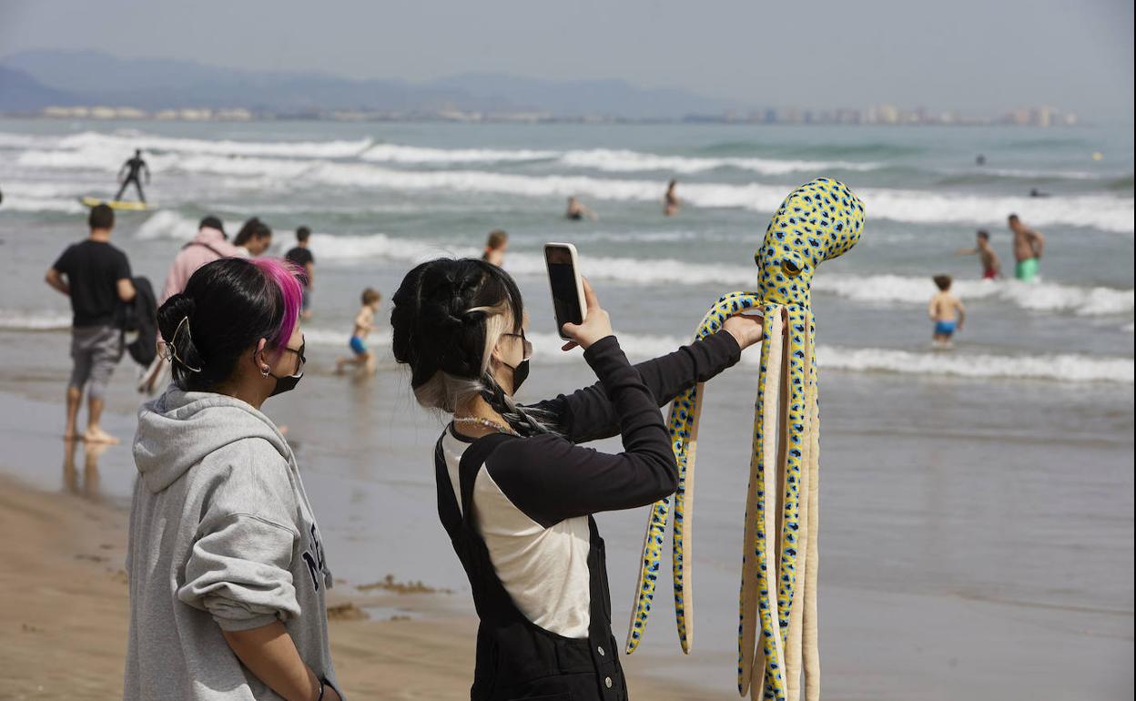 Dos jóvenes fotografían un peluche este viernes en la playa de la Malvarrosa. 