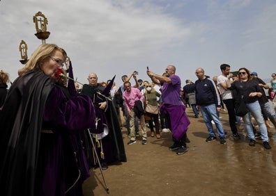 Imagen secundaria 1 - Oración en la orilla, una mujer besa un clavel antes de lanzarlo al mar y Cristo portado por cofrades. 