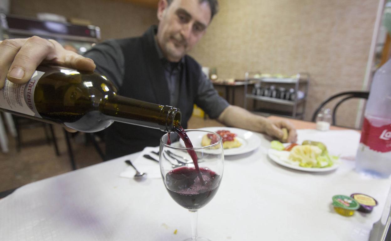 Un hombre se sirve una copa de vino en un restaurante de Valencia. 