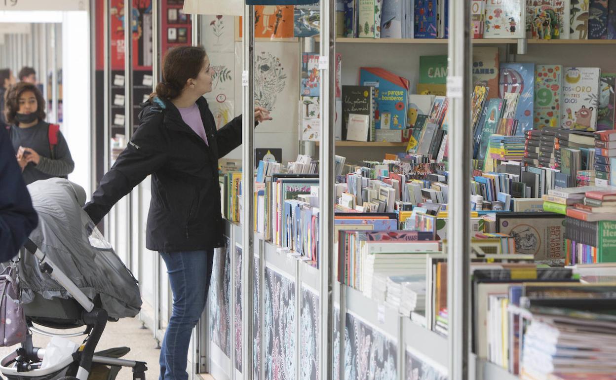 Una mujer junto al cochecito de su hijo ante una caseta de la Fira del Llibre. 