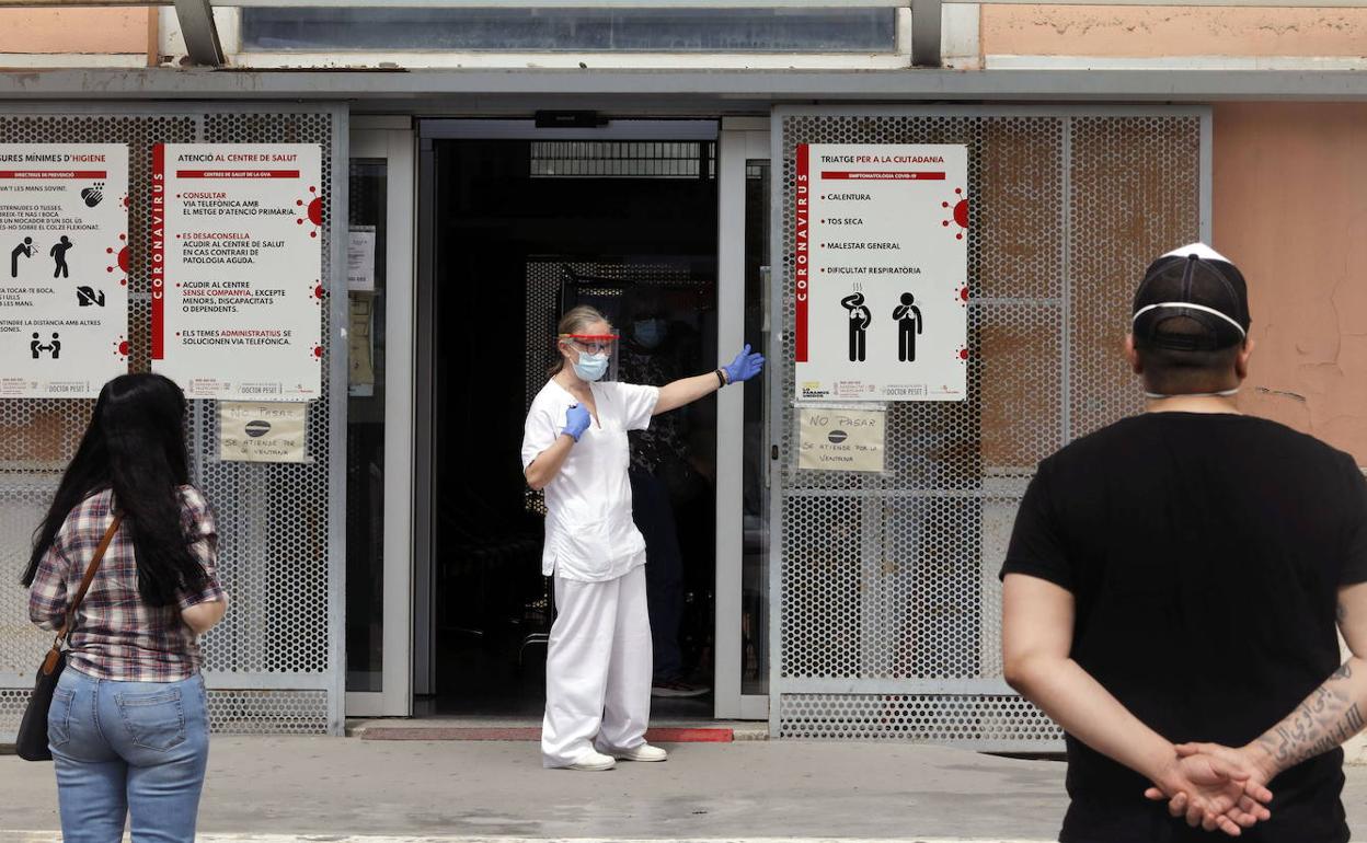 Dos usuarios y una profesional sanitaria a las puertas de un centro de salud.