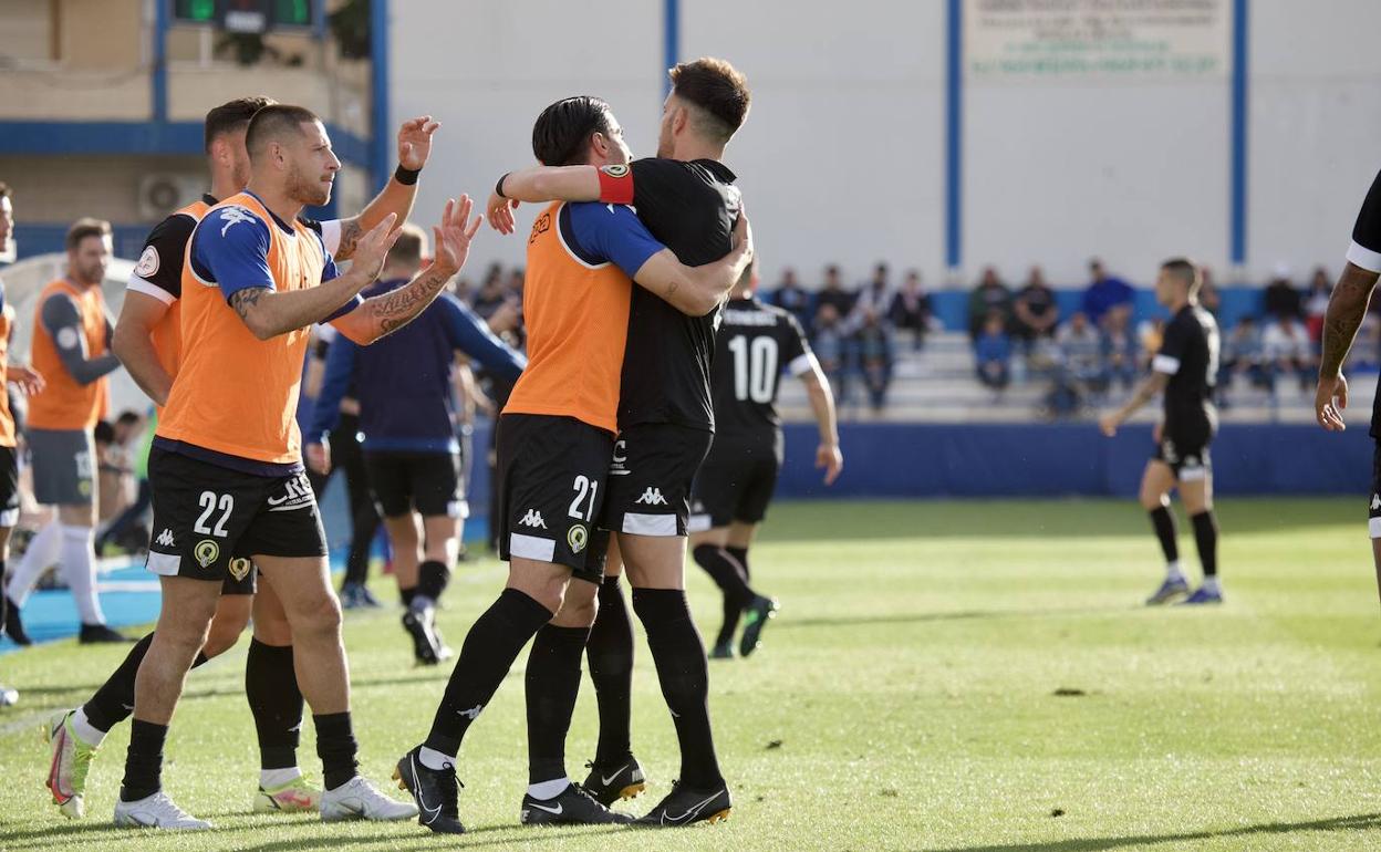 Los jugadores del Hércules Chuli y Acuña abrazan a Raúl Ruiz Matarín. 