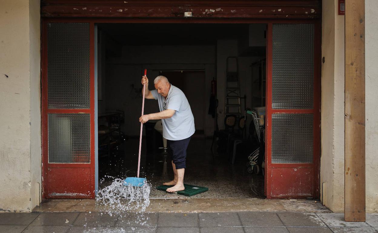 Un hombre achica el agua de su establecimiento. 